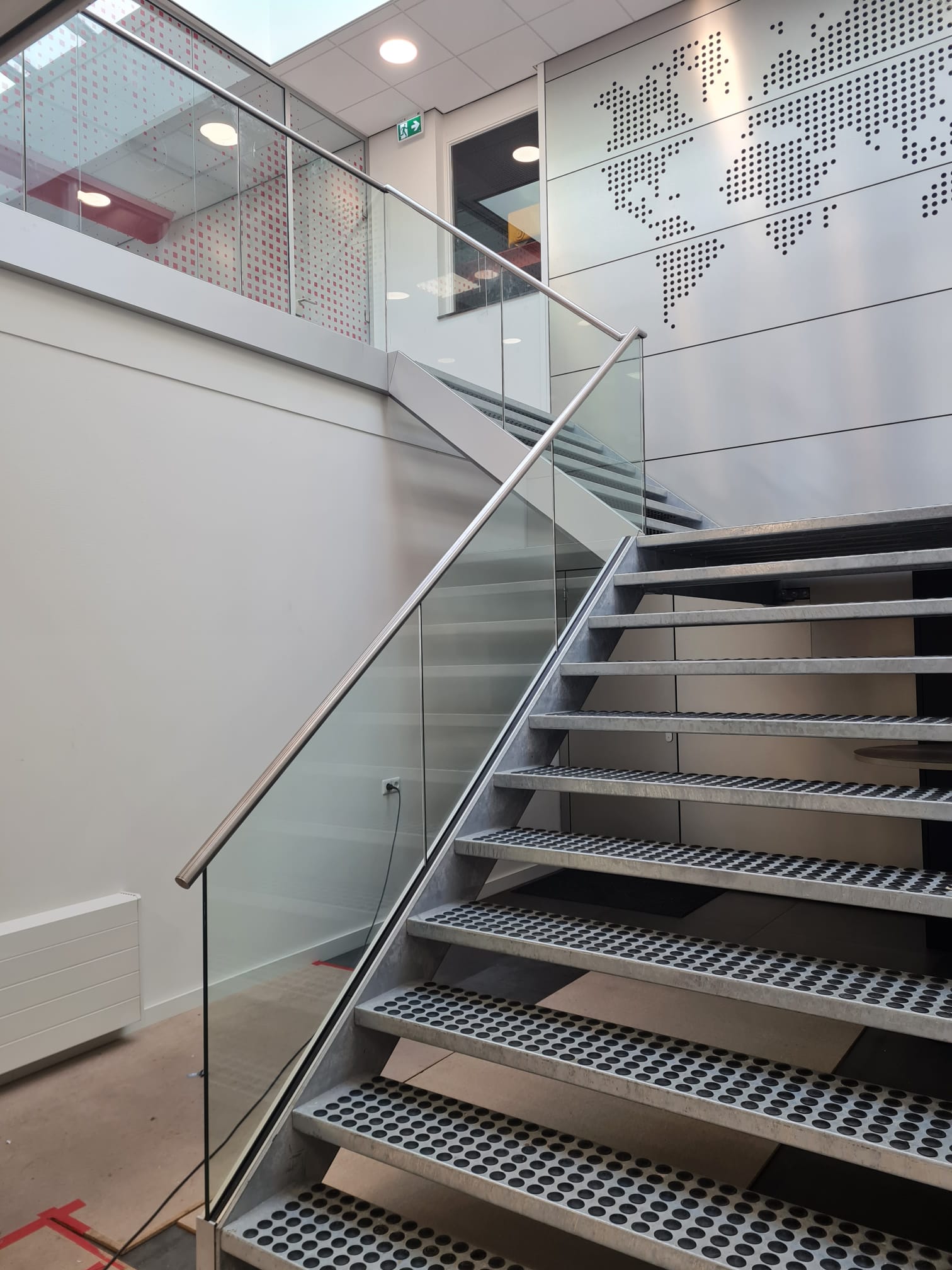 Rechte trap met treden met rubberdoppen en een glasleuning